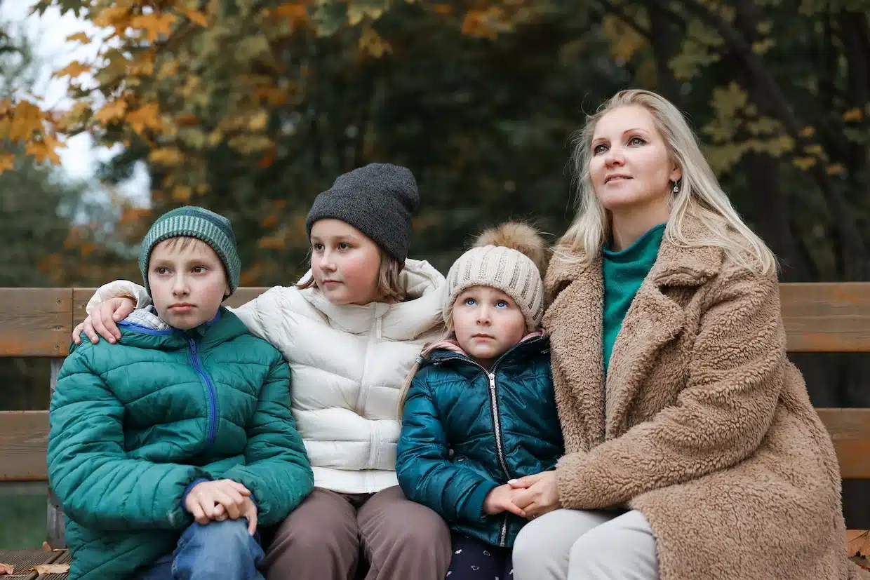 Family sitting on a bench in autumn park.