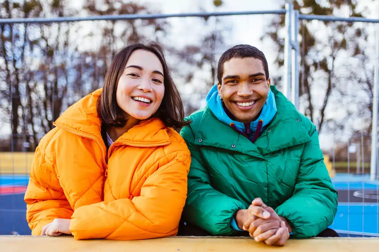 Smiling friends in colourful winter jackets outdoors.