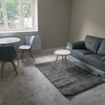 Modern living room with grey sofa and dining set.